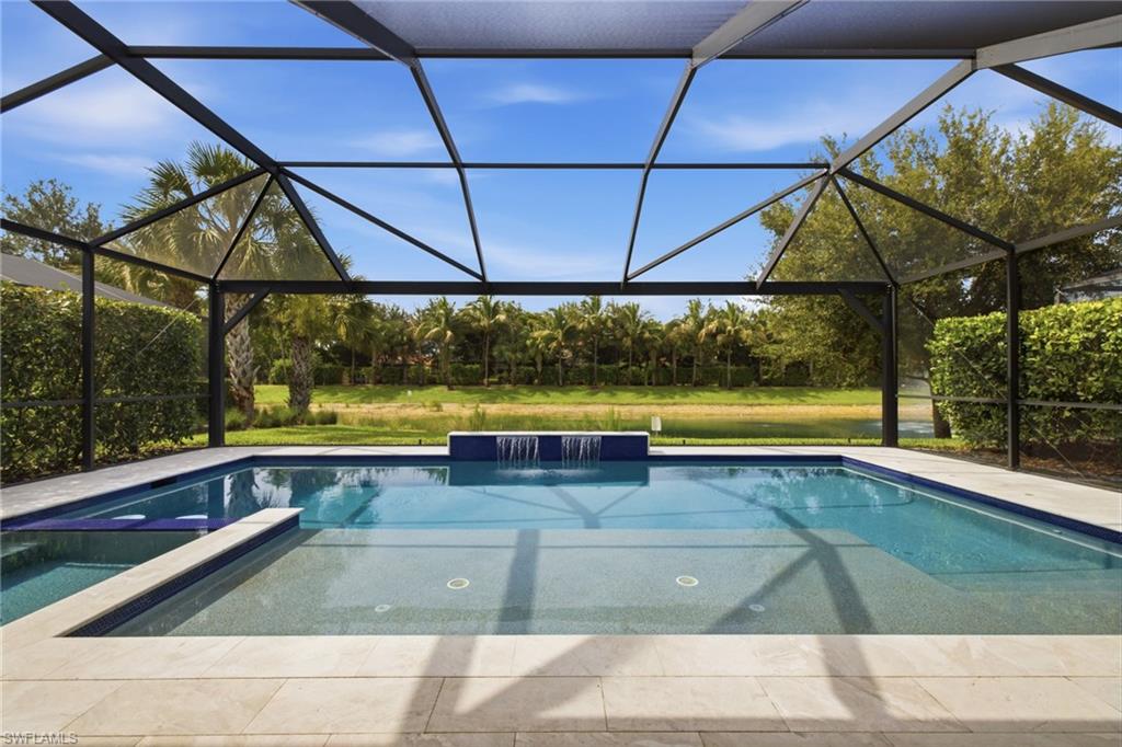 Screened lanai featuring a swimming pool, integrated spa, and a waterfall water feature