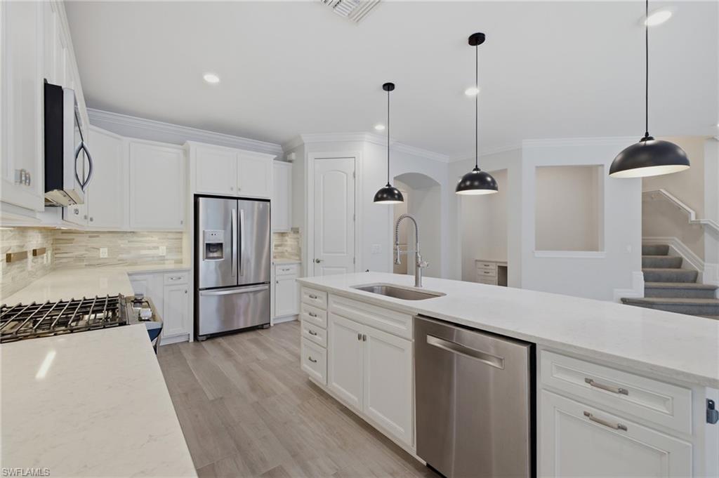 Modern kitchen featuring white cabinetry, light-toned countertops, stainless steel appliances, and a tile backsplash