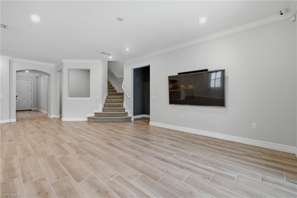 Spacious main living area featuring wood-finish tile flooring, recessed lighting, and crown molding