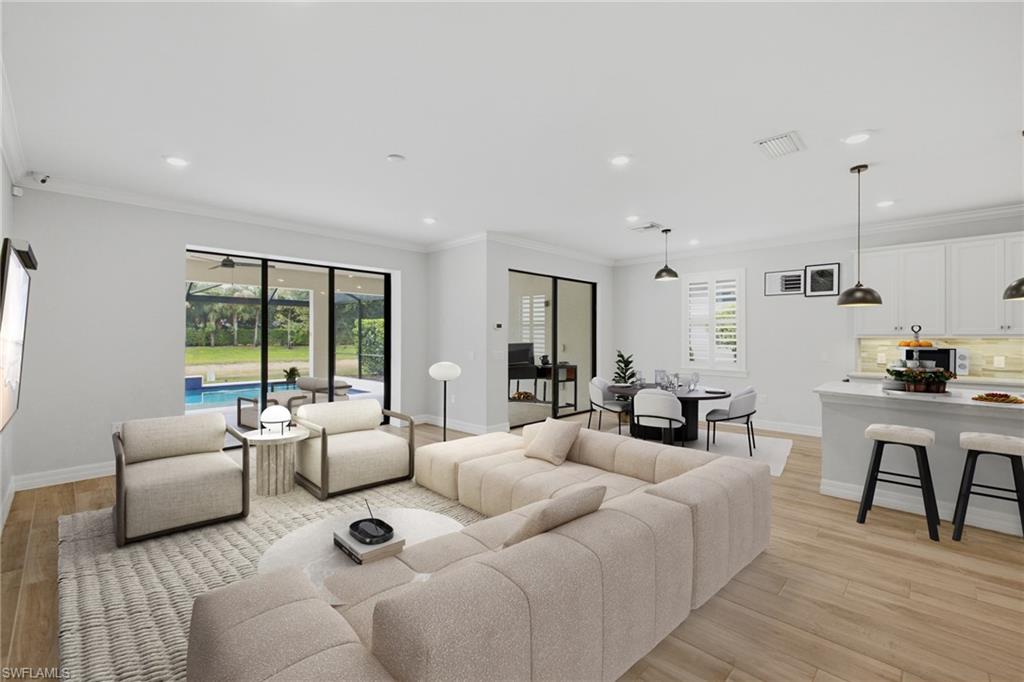 Open-concept living space featuring wood-finish flooring, recessed lighting, and crown molding