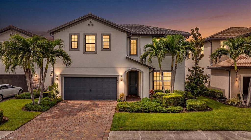 Contemporary-style residence featuring a two-car garage, extensive paver driveway, and a tiled roof