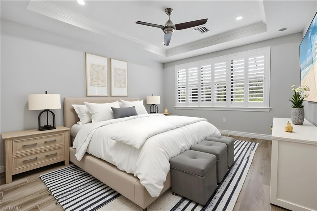 Spacious room featuring tray ceilings with recessed lighting, a modern ceiling fan, and wood-finish flooring
