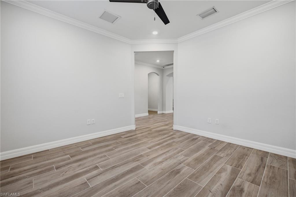 Spacious interior room featuring wood-finish flooring, crisp white walls, and a recessed lighting fixture