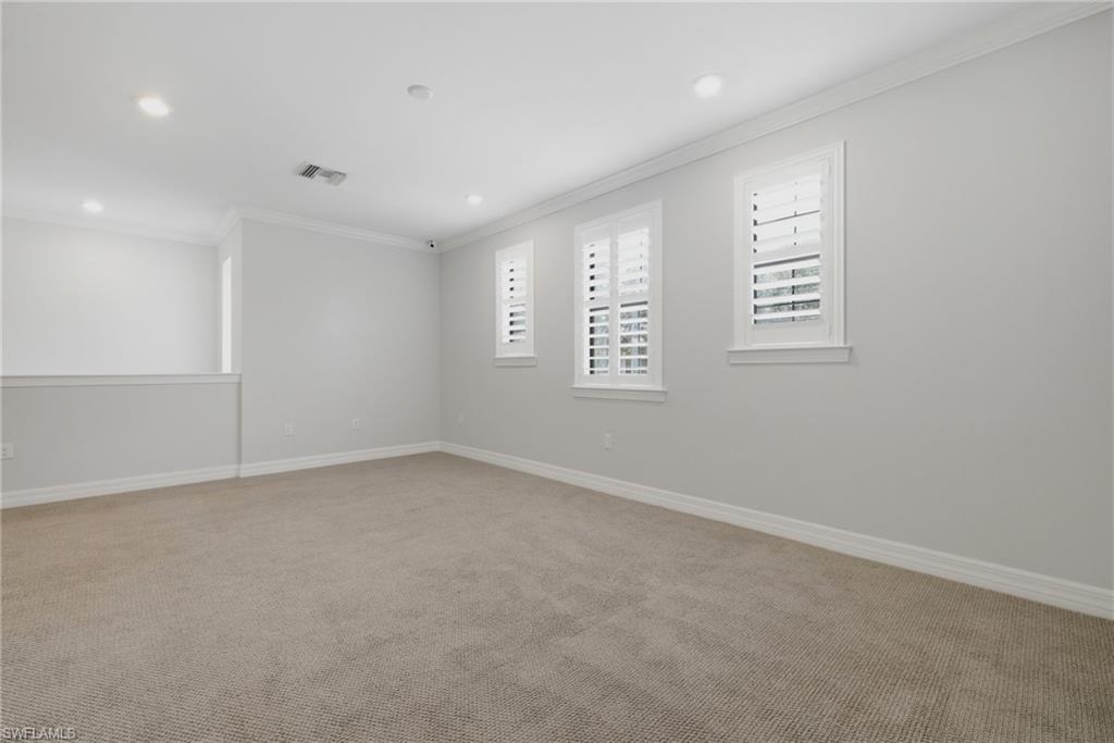 Carpeted room featuring white plantation shutters, recessed lighting, and crown molding
