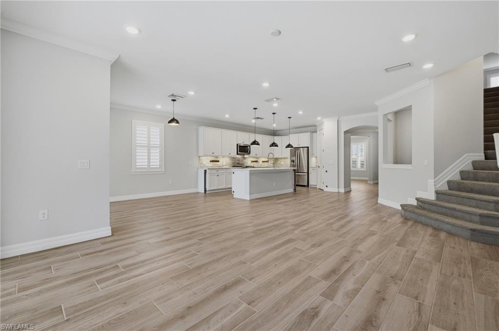 Open-concept living space featuring wood-finish flooring, recessed lighting, and a modern kitchen with white cabinetry and an island