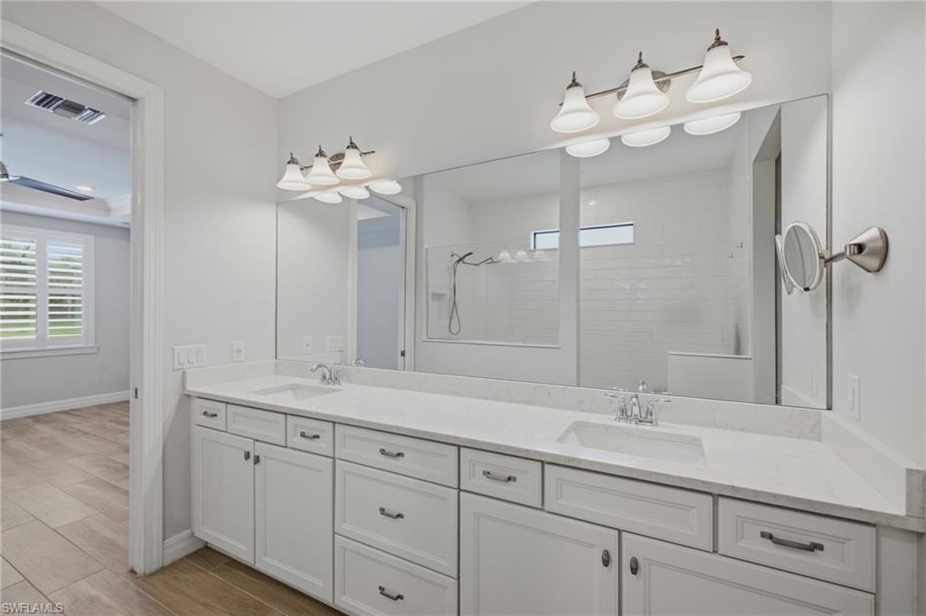 Dual vanity with white cabinetry, light-toned countertops, and brushed nickel hardware