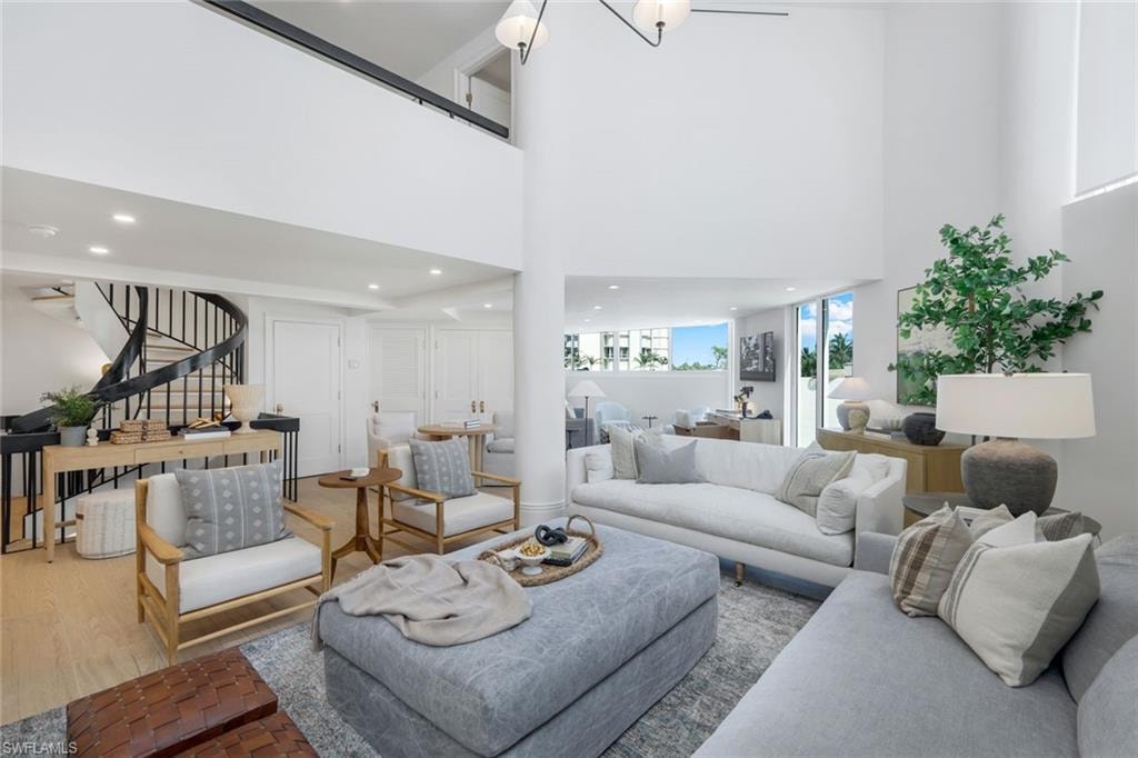Living room with stairs, a towering ceiling, recessed lighting, and wood finished floors