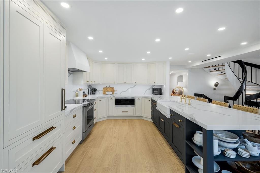 Kitchen with white cabinets, light stone countertops, a peninsula, a breakfast bar area, and recessed lighting