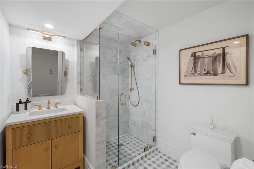 Bathroom featuring vanity, a marble finish shower, and recessed lighting