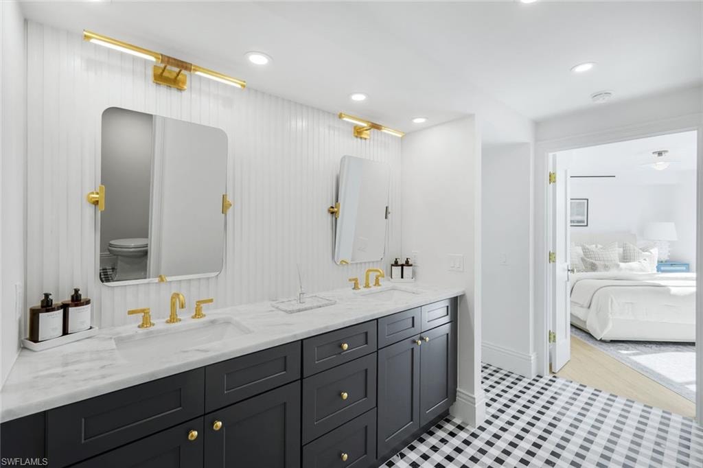 Ensuite bathroom with double vanity, recessed lighting, and light tile patterned floors
