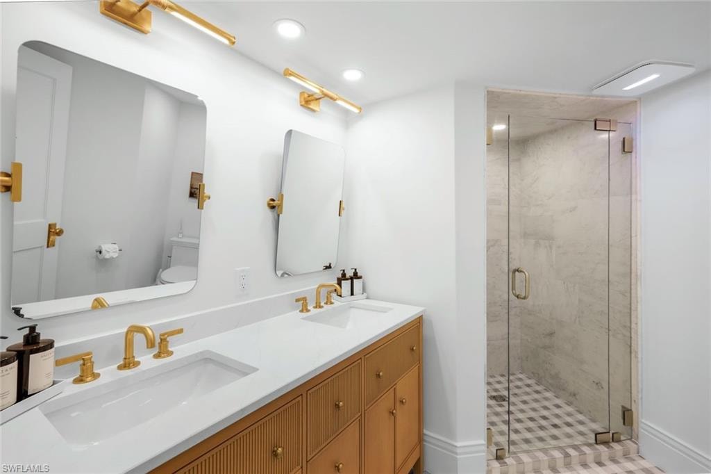 Bathroom with a shower stall, double vanity, and recessed lighting