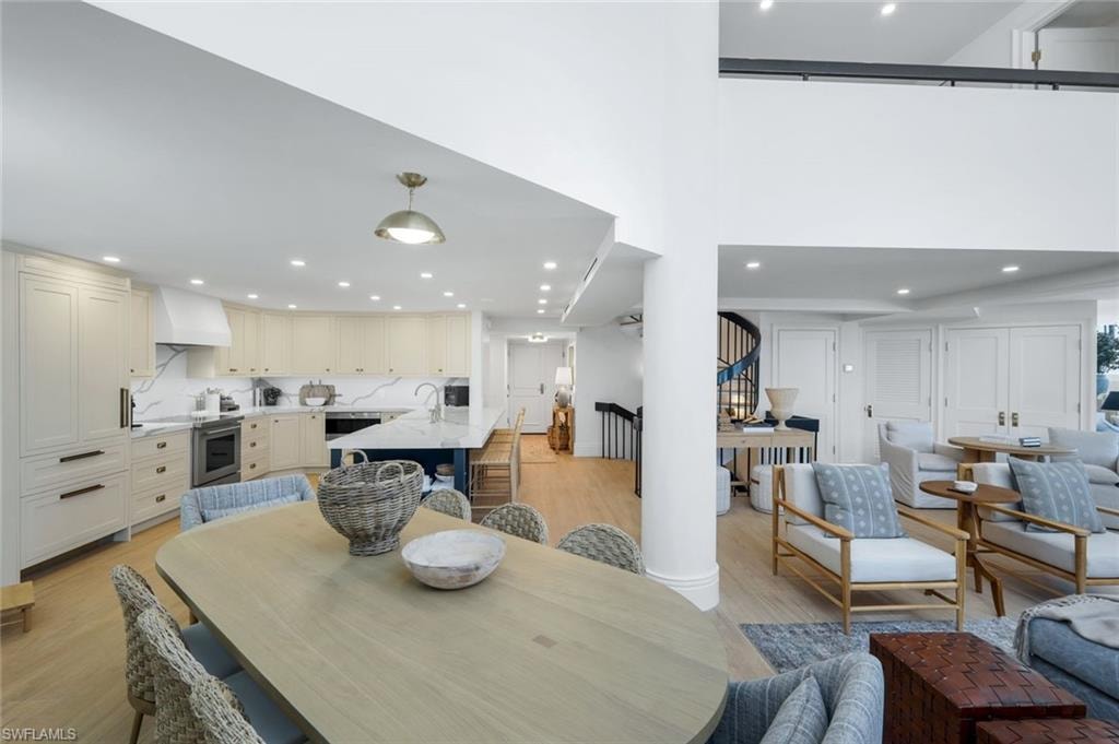 Dining room featuring light wood finished floors, recessed lighting, and a high ceiling