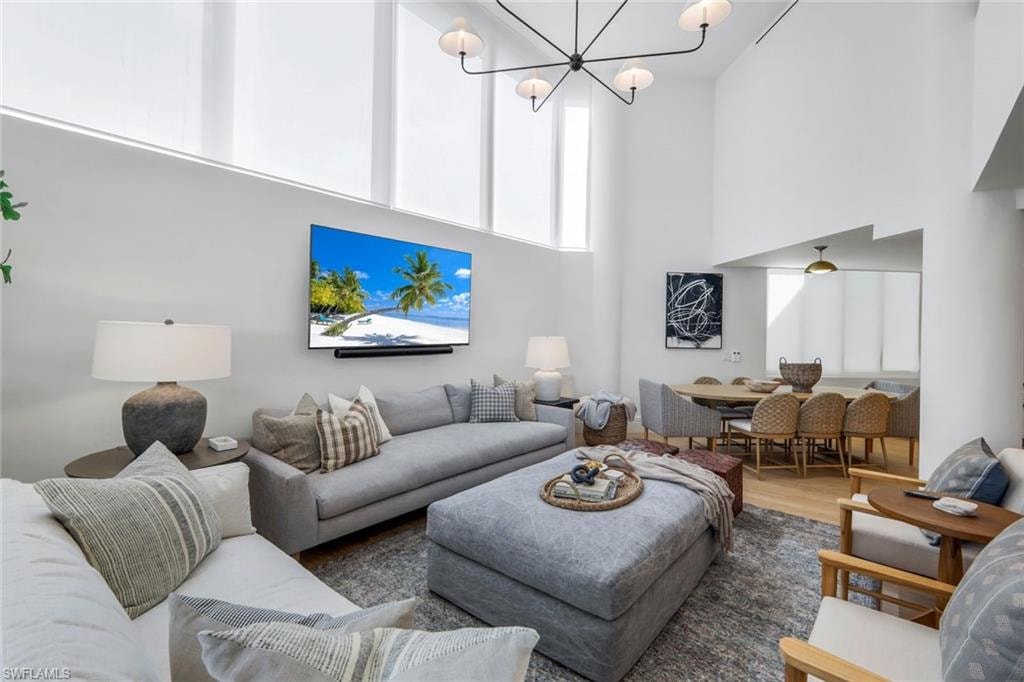 Living room with a towering ceiling, wood finished floors, and a chandelier
