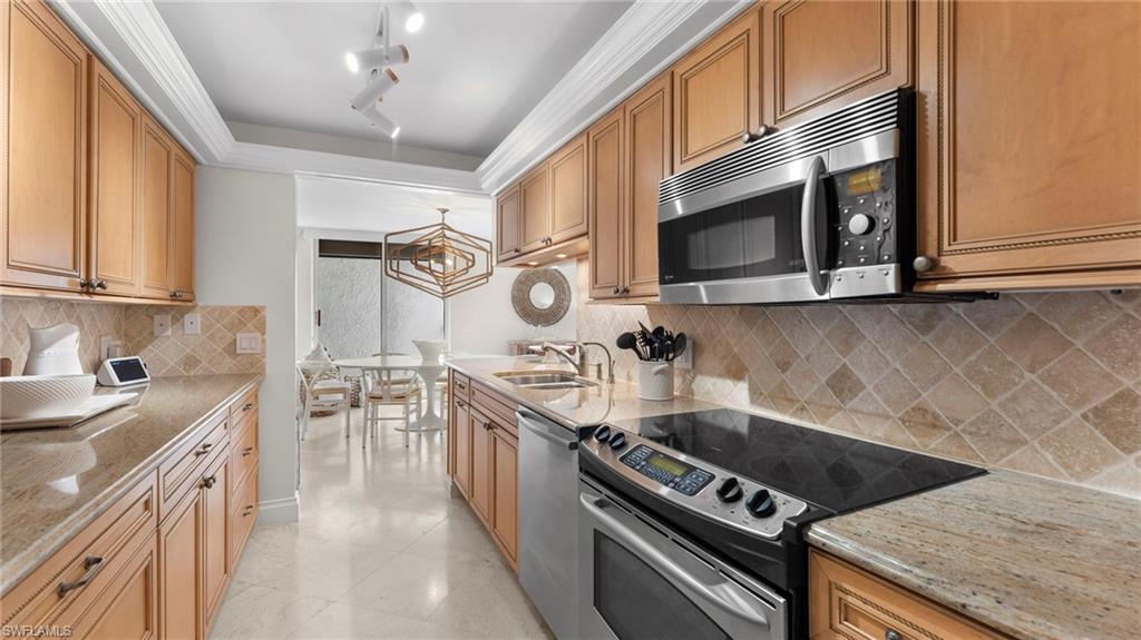 Kitchen featuring light stone countertops, stainless steel appliances, sink, and decorative backsplash