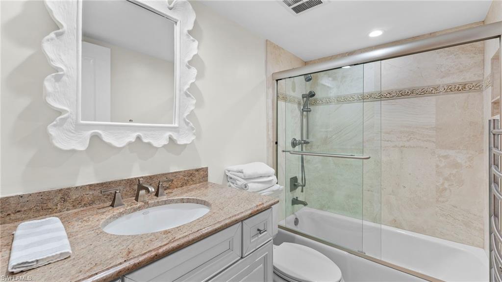 Full bathroom with vanity, combined bath / shower with glass door, and toilet