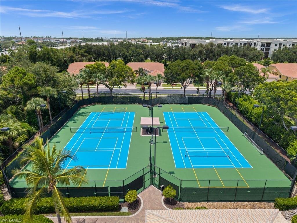 Two full-size tennis courts with blue playing surfaces and green surrounds, enclosed by dark fencing