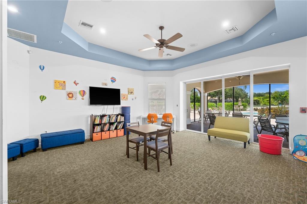 Spacious room featuring tray ceilings with recessed lighting and a ceiling fan, carpet flooring, and white walls with a blue ceiling accent
