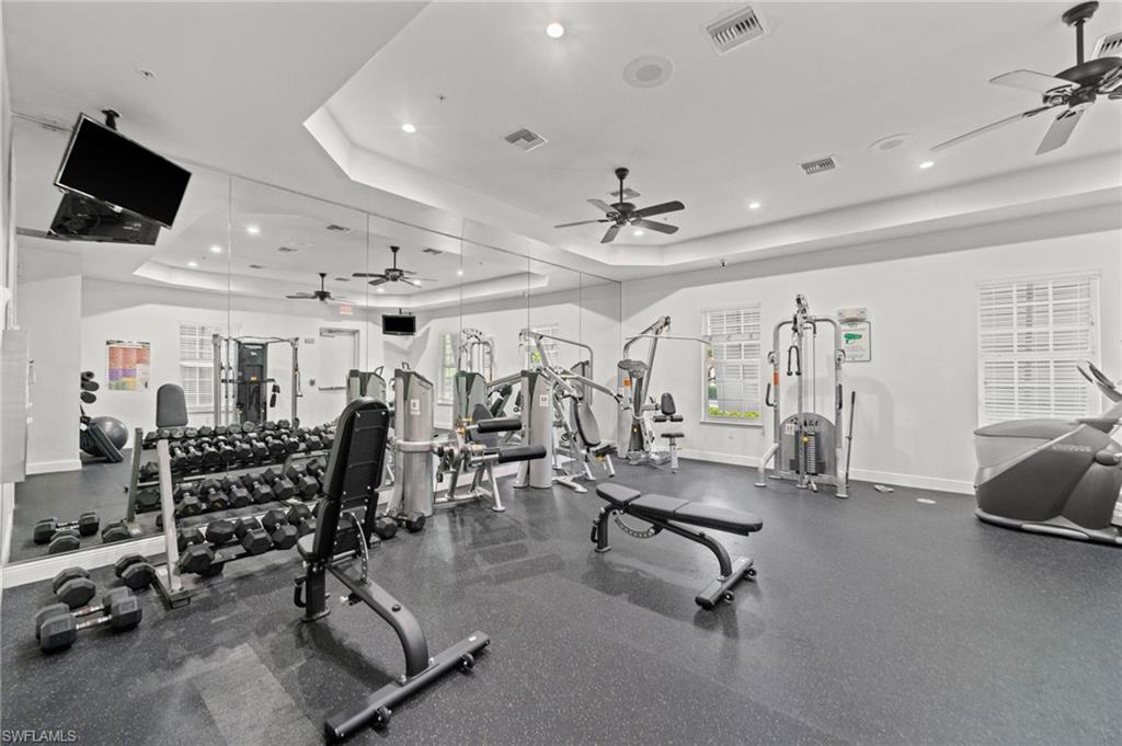 Dedicated fitness space featuring rubber flooring, mirrored wall, and recessed lighting