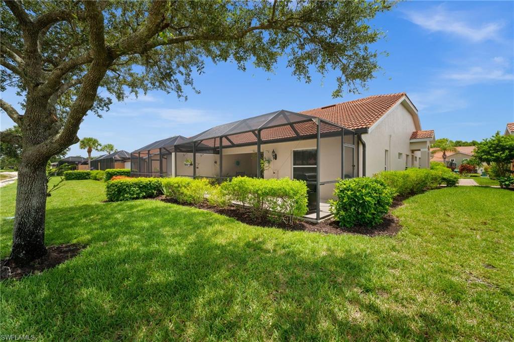 Rear exterior featuring a screened-in patio, stucco siding, and a red tile roof