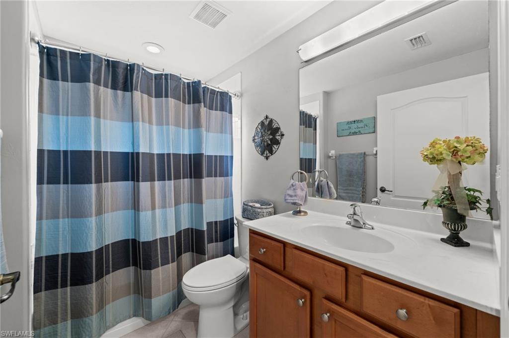 Full bathroom featuring a single vanity with wood-finish cabinetry, a white countertop, and an integrated sink