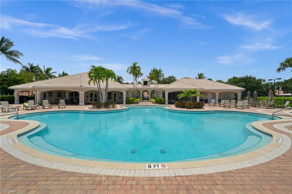 Expansive outdoor swimming pool with a 5-foot depth marker, surrounded by brick paver decking