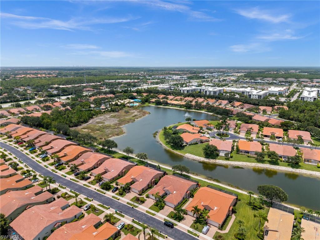 Aerial perspective of a residential community featuring a lake and established landscaping