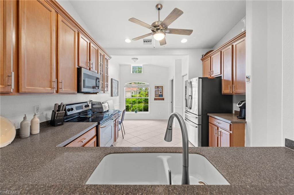 Kitchen featuring wood cabinetry, dark countertops, built-in microwave, and stainless steel appliances