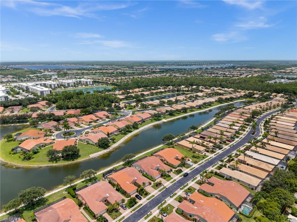 Aerial perspective of a residential community featuring multiple water bodies, abundant mature trees, and varying roof styles