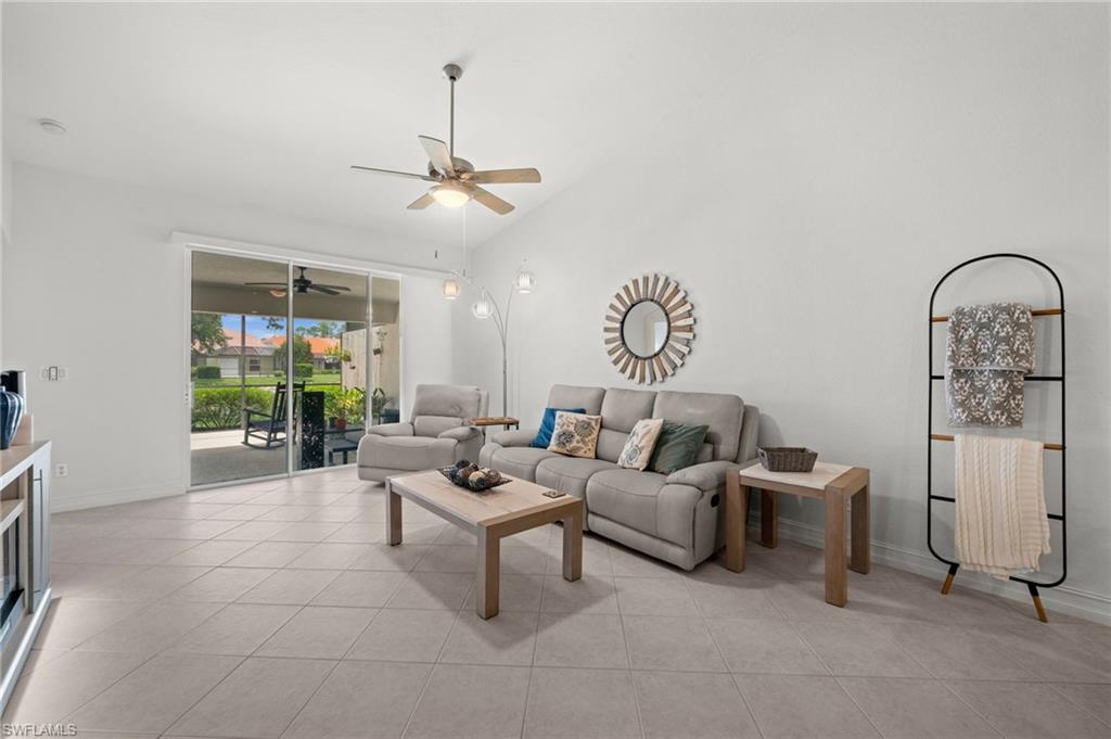 Living area featuring vaulted ceilings, large format tile flooring, and a sliding glass door opening to a screened lanai