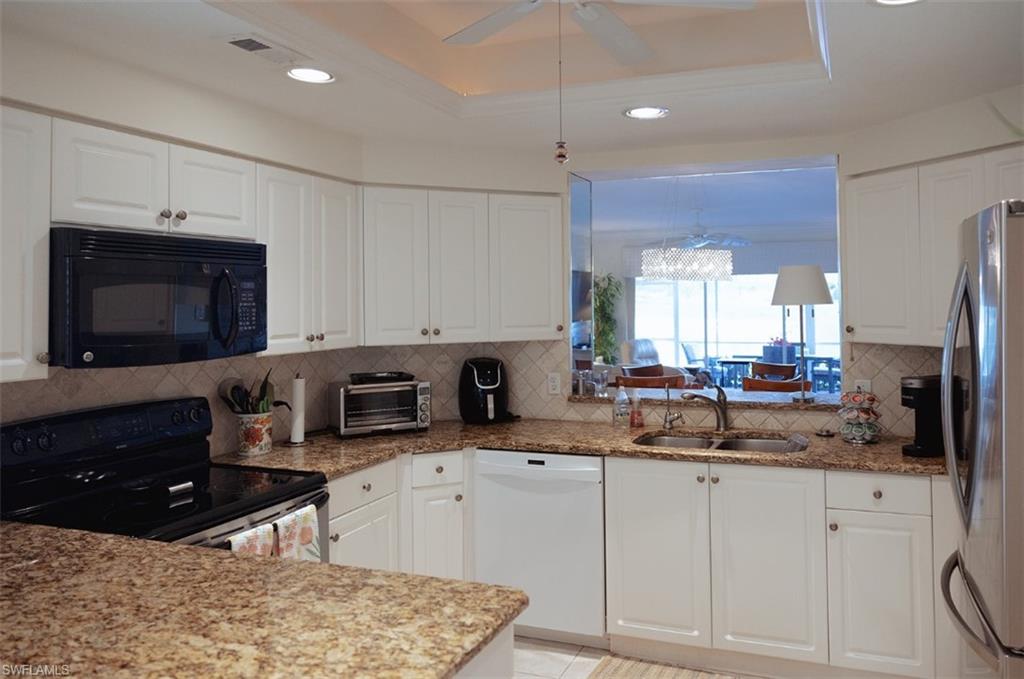 Kitchen featuring electric range, dishwasher, stainless steel refrigerator, a tray ceiling, and sink