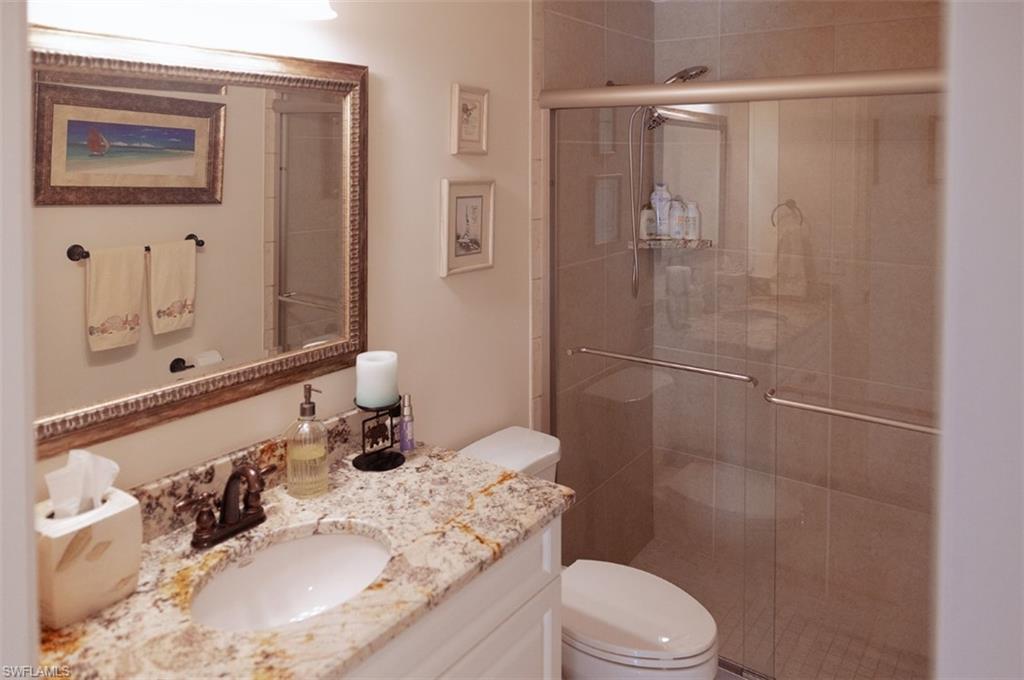 Bathroom featuring walk in shower, toilet, and vanity