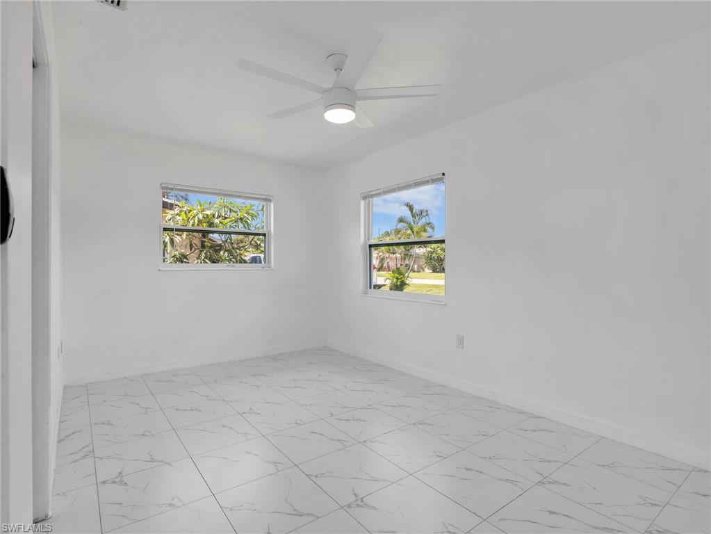 White tile flooring with a subtle veined pattern, bright white walls, and two windows providing natural light