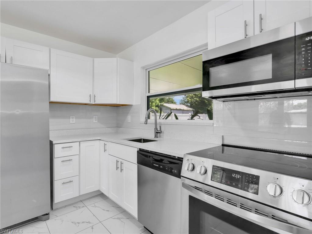 Contemporary kitchen featuring white cabinetry, light-colored countertops, a tile backsplash, and stainless steel appliances