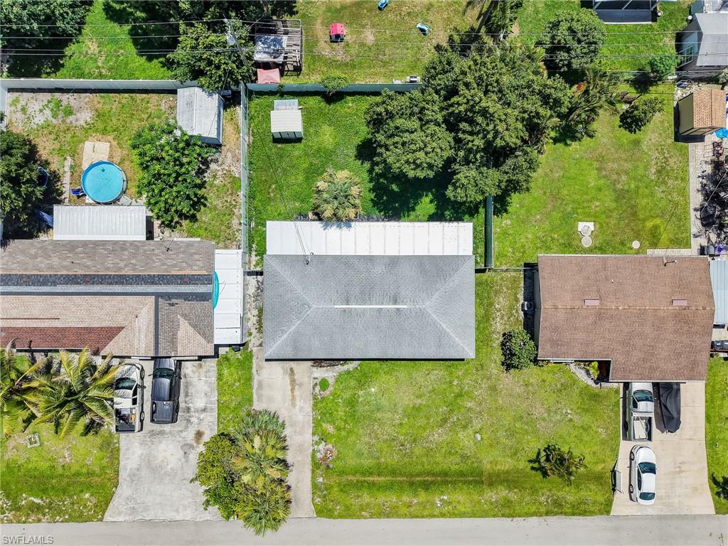 Aerial perspective showcasing a residential property with a gray shingle roof, concrete driveway, and established front lawn