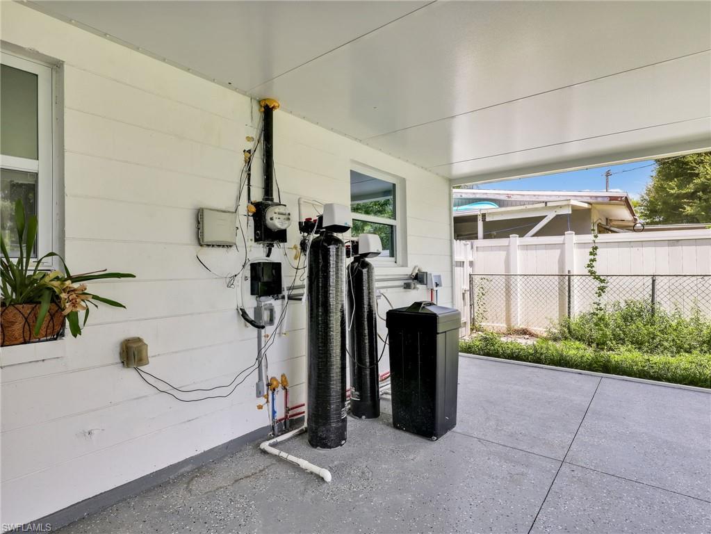 Covered patio with a painted concrete surface, featuring a water filtration system and utility hookups