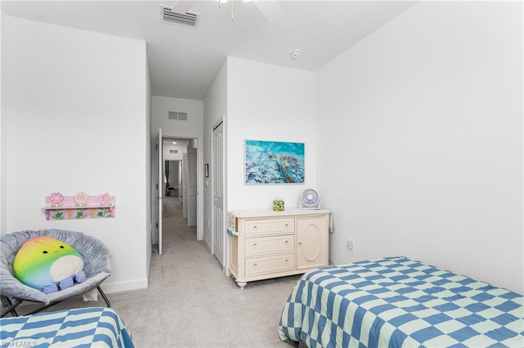 Spacious secondary bedroom with high ceilings, soft carpeting, ceiling fan, and generous closet space