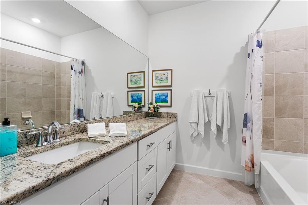 A full hallway bathroom includes a large vanity with granite countertop, tub/shower combo, and linen storage