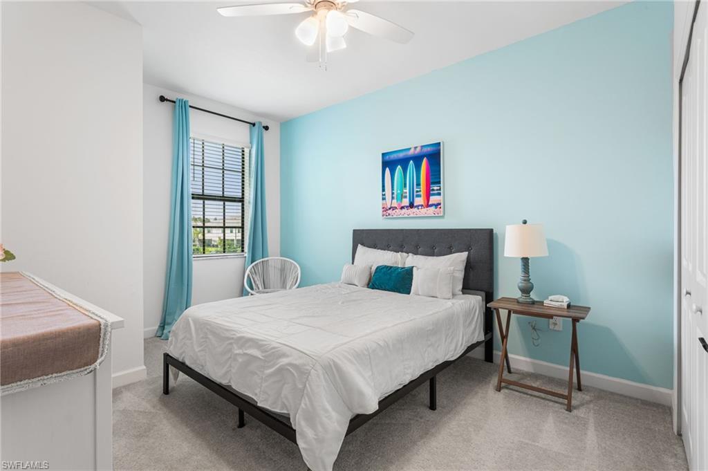 Bright third bedroom featuring a cheerful accent wall, ceiling fan, generous closet space, and plenty of natural light