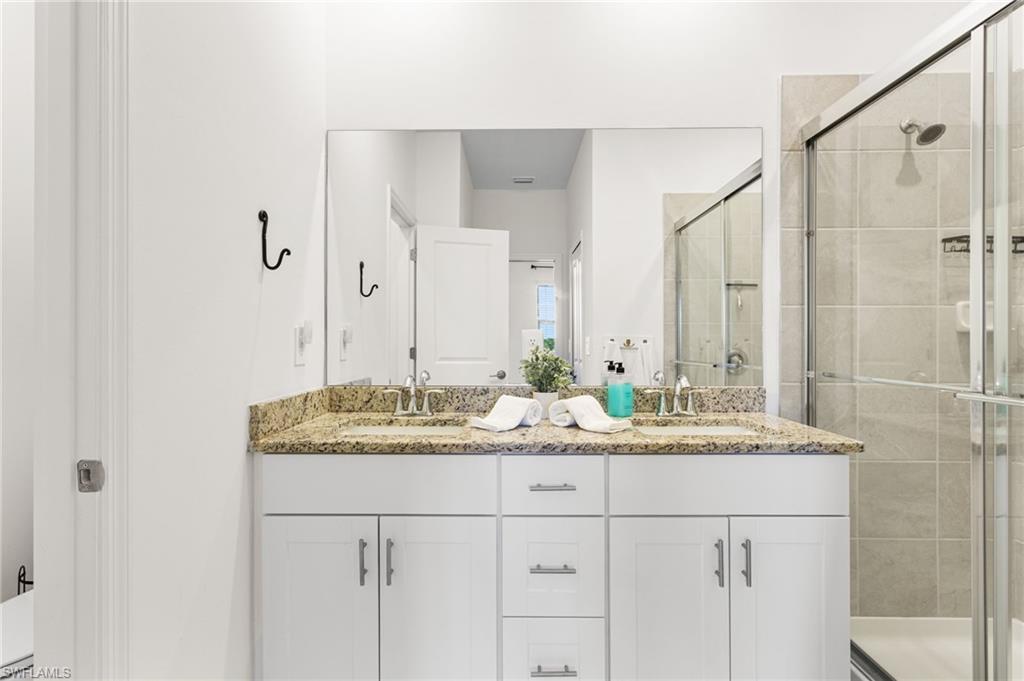 The ensuite bath offers granite countertops, dual sinks, and a glass-enclosed walk-in shower