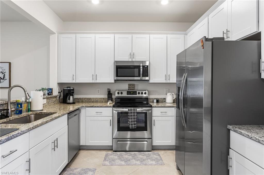 The spacious kitchen boasts granite countertops, stainless steel appliances, a deep sink, and white shaker cabinets