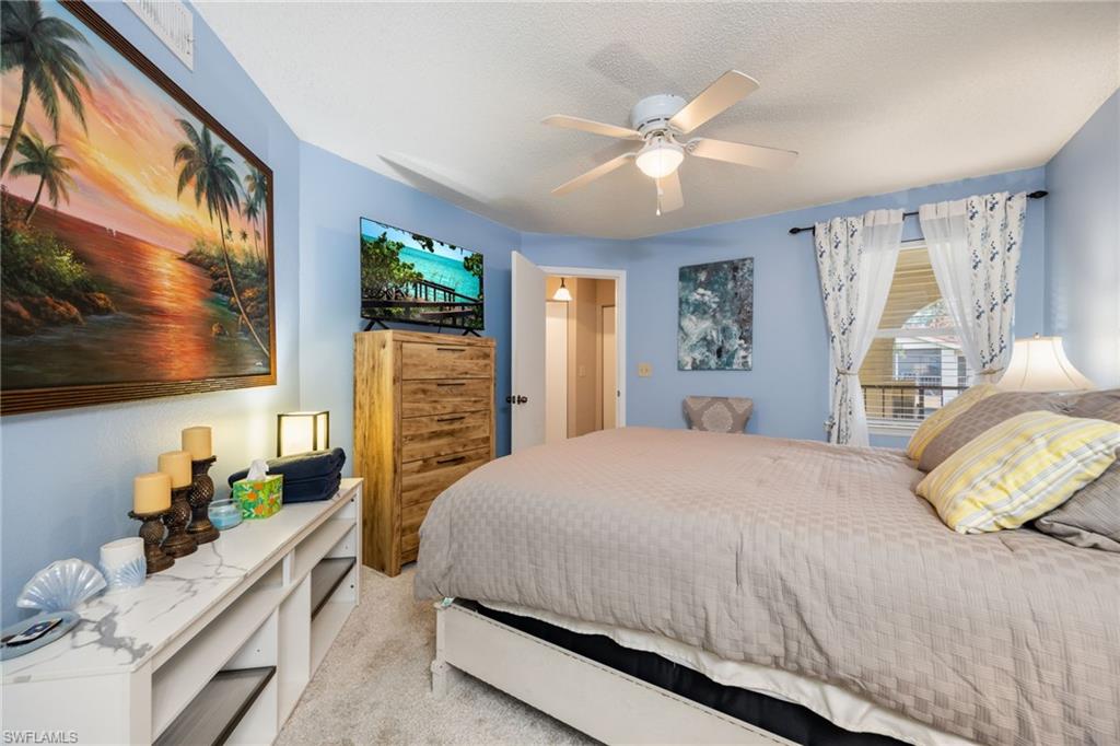 Carpeted bedroom featuring a ceiling fan with light, a window with curtains, and a wood-finish dresser