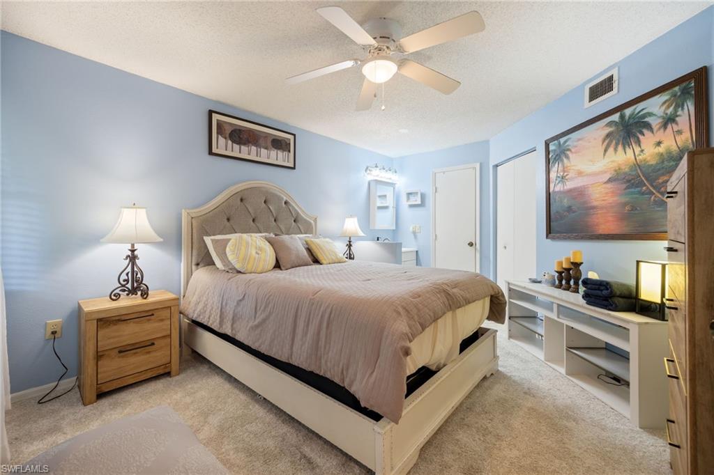 Carpeted bedroom with a ceiling fan, light blue walls, and a tufted headboard