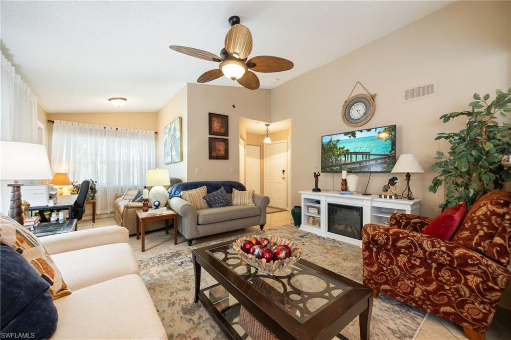 Spacious living area featuring light-toned walls, a decorative ceiling fan, and tiled flooring