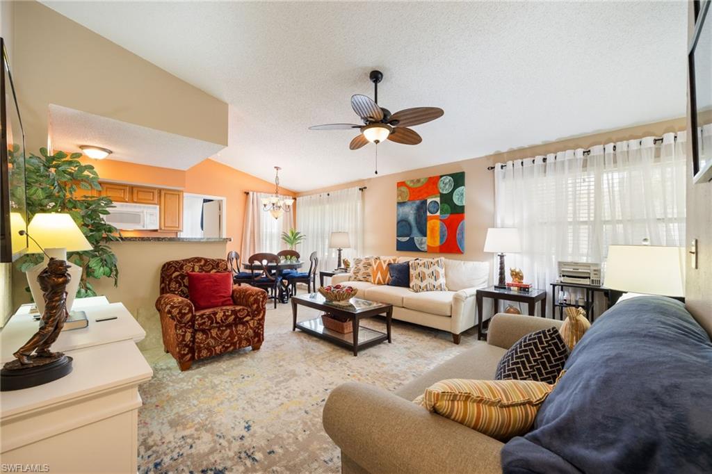 Open-concept living area featuring vaulted ceilings, a ceiling fan, and light wall tones