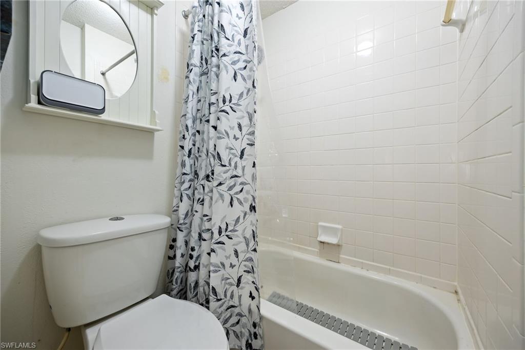 White-tiled bath with a standard tub and toilet
