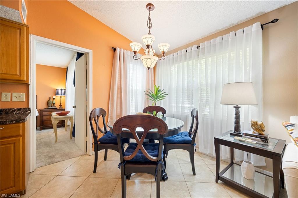 Dining area featuring tile flooring, a multi-light chandelier, a large window with sheer drapes, and an open doorway to an additional room