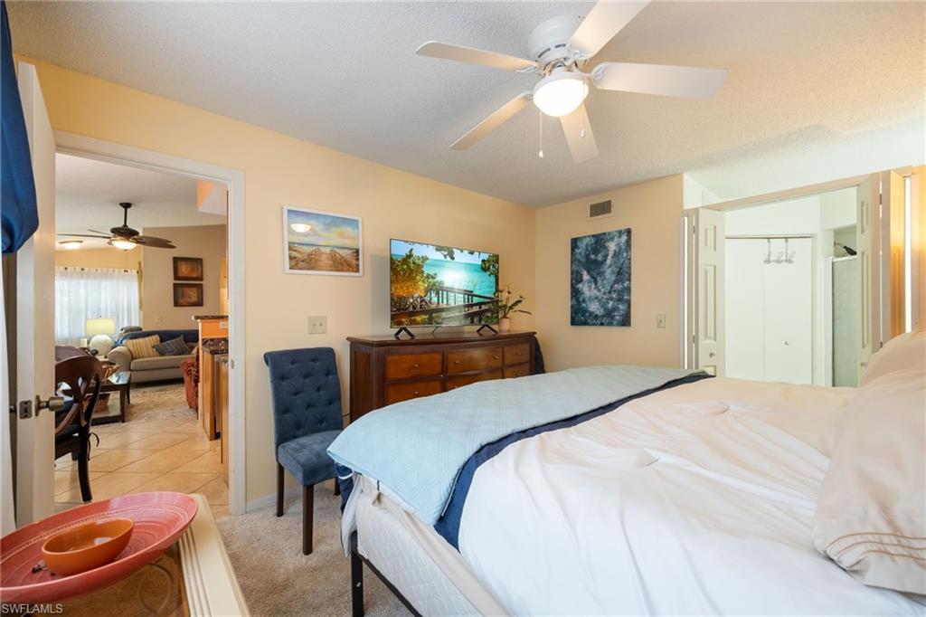 Bedroom featuring carpet flooring, a ceiling fan with integrated lighting, and a bi-fold closet with mirrored doors