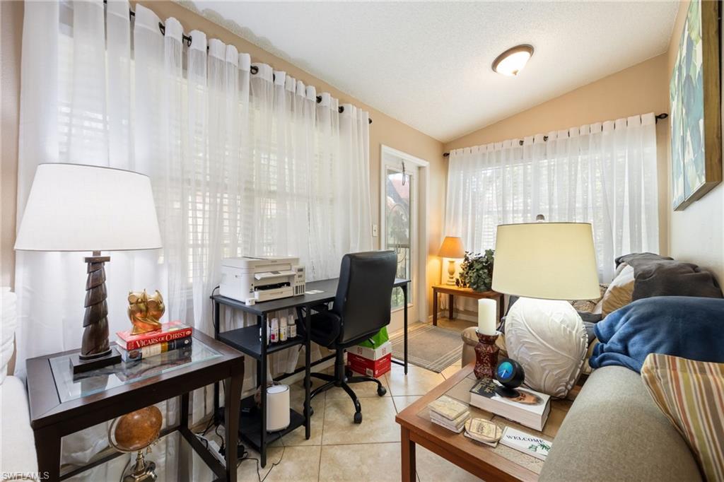 Versatile room featuring ample natural light from multiple windows, vaulted ceiling, and durable tile flooring