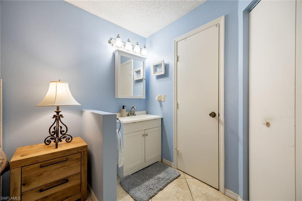 Bathroom vanity with white cabinetry, integrated sink, and wall-mounted light fixture