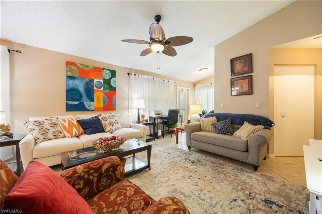 Open-concept living area featuring a ceiling fan, vaulted ceiling, and neutral wall tones